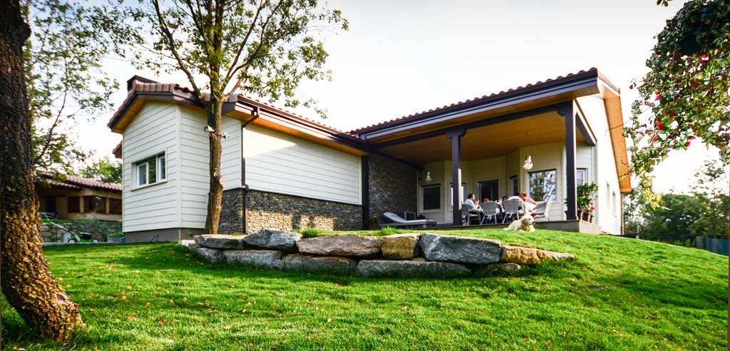 Imagen de La importancia de los porches en verano en Canexel jardín y fachada casa de madera